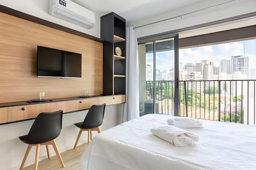 a bedroom with a bed with chairs and a television at Nik Perdizes in Sao Paulo