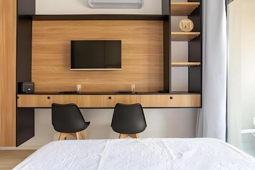 a bedroom with a desk with a tv and two chairs at Nik Perdizes in Sao Paulo