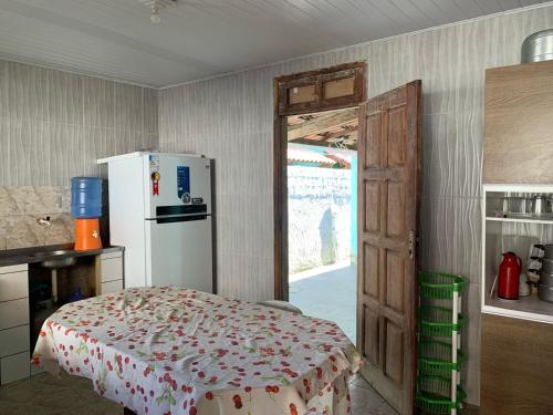 una cucina con tavolo, frigorifero e porta di Casa de praia em Vilage da Barra a Ilhéus
