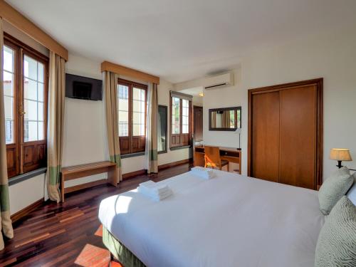 a bedroom with a large white bed and windows at Hotel Vale Verde in Furnas
