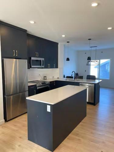 a kitchen with black cabinets and stainless steel appliances at Bedroom in Upland B in Edmonton