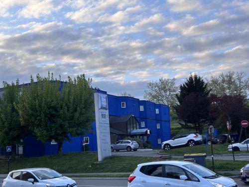 two cars parked in front of a blue building at ibis budget Belfort Centre in Belfort
