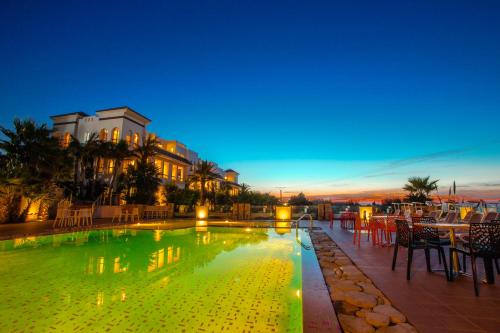 a swimming pool with tables and chairs in front of a building at Mnar Castle in Tangier