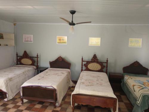 a room with two beds and a ceiling fan at Suites Delicia in Passa Quatro