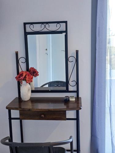a mirror on a table with a vase of flowers at Calypso Heaven in Santorini