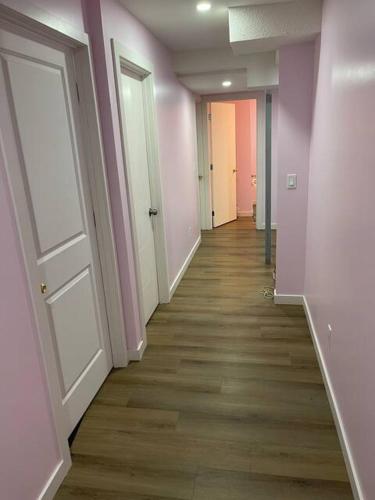 an empty hallway with pink walls and wooden floors at Bedroom in Upland C in Edmonton