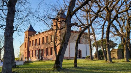 un grand bâtiment en briques avec une tour en haut dans l'établissement Château La Bordette 15mn Toulouse Vue Pyrénées, Piscine, à Clermont-le-Fort
