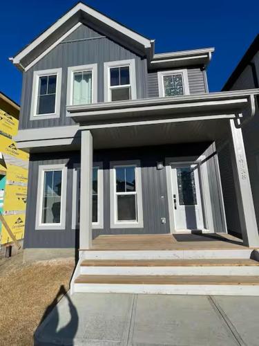 a gray house with a front porch and a person standing in front at Bedroom in Upland D in Edmonton