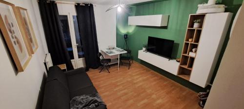 a living room with a couch and a desk and a television at Charmant studio à Castres in Castres