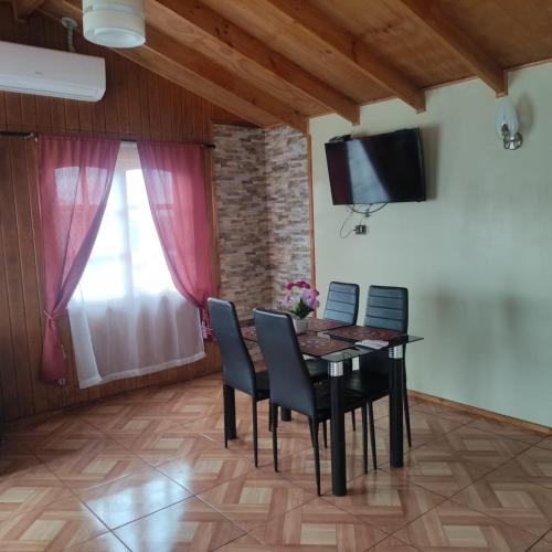 a dining room with a table and chairs and a television at Cabaña la colina in Castro