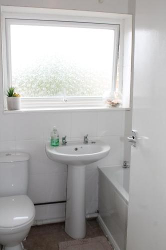 a bathroom with a sink and a toilet and a window at 5 Sea View Walk - unique beachfront location - pets welcome - free parking in Pakefield