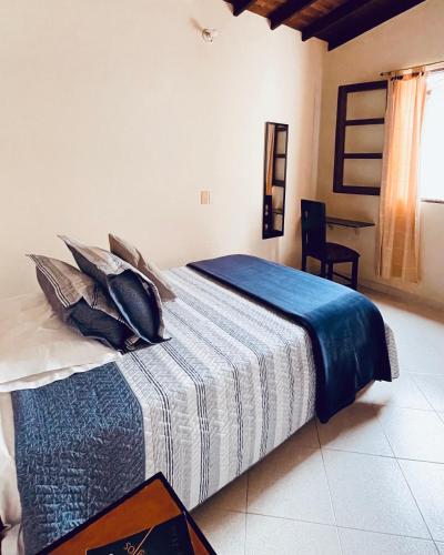a bedroom with a bed with a blue and white blanket at HOTEL PLENITUD JARDÍN - Transporte, Tours y Más in Jardin