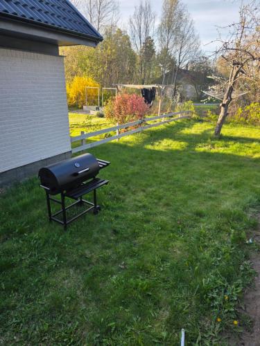 a grill sitting in the grass in a yard at Lugn & Ro på Vändstigen in Nybro