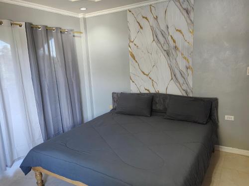 a bedroom with a blue bed with a painting on the wall at Eazy Stay Room Rental in Panglao