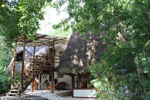 a house with a thatched roof and a staircase at Posada del Cerro in El Remate