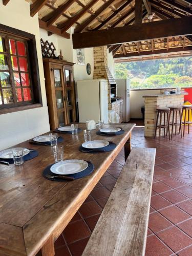a large wooden table in a room with a kitchen at Casa em Secretário a 800 metros do centro de Secretário chacaradosolsecretario in Petrópolis
