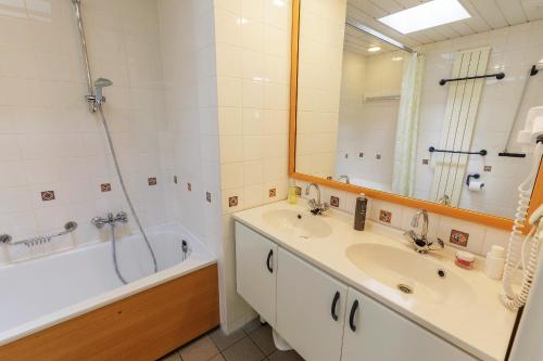 a bathroom with two sinks and a tub and a shower at Center Parcs Bispinger Lüneburger Heide in Bispingen