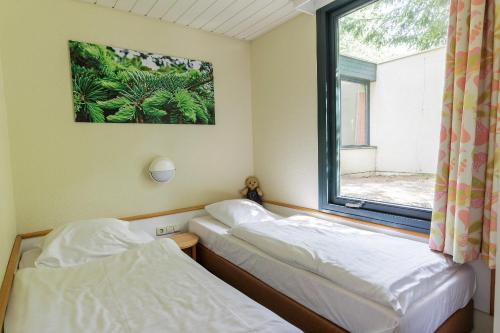 two beds in a room with a window at Center Parcs Bispinger Lüneburger Heide in Bispingen