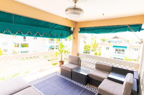 a balcony with a couch and chairs and a large window at Dejai On The Bay in Montego Bay
