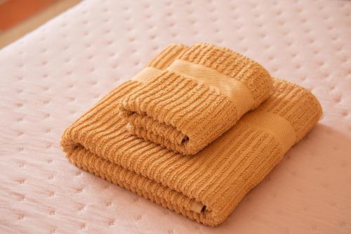 a yellow knit blanket on top of a bed at BE LOST - Guest House in Pedra Do Ouro