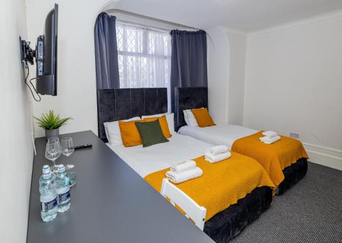 a room with two beds and a table with bottles of water at Woodford Hotel in London