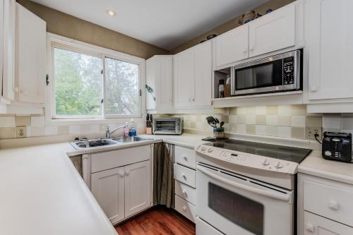a kitchen with white cabinets and a sink and a microwave at Artistic Haven By The Beach in Wiarton