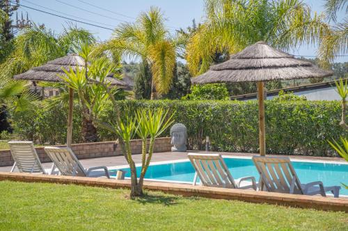 a group of chairs and umbrellas next to a pool at Quinta Gomes in Lagos