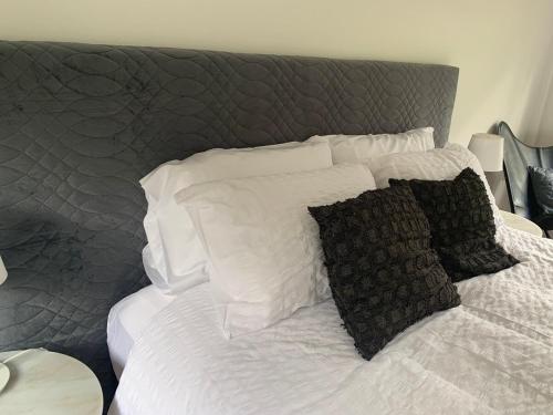 a bed with white sheets and black pillows at Clarendon Country Cottage private retreat in Clarendon