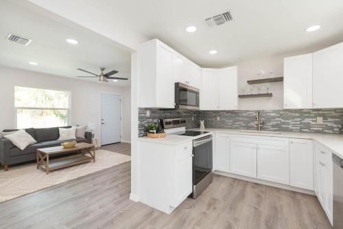 Una cocina con gabinetes blancos y una sala de estar. en 3 bedrooms 2 bathrooms Charming Gulfport home near the beach, en San Petersburgo