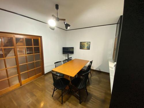 a dining room with a wooden table and chairs at 勝山貸切民泊三つ子の魂 福井県立恐竜博物館まで車で10分 発坂駅から徒歩5分 in Katsuyama