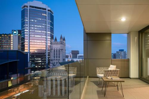a balcony with chairs and a view of a city at Quest on Hobson Serviced Apartments in Auckland