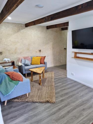 a living room with a couch and a tv at The Bullock & Bridle Retreat at 58 in Mintaro