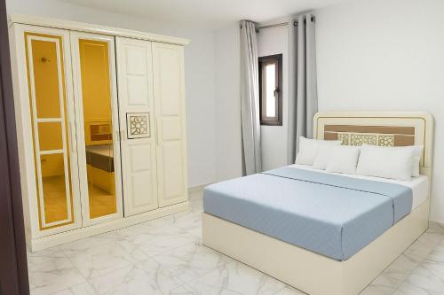 a white bedroom with a blue bed in it at Luxurious Chalet in Port Said Governorate with Breathtaking View in Port Said