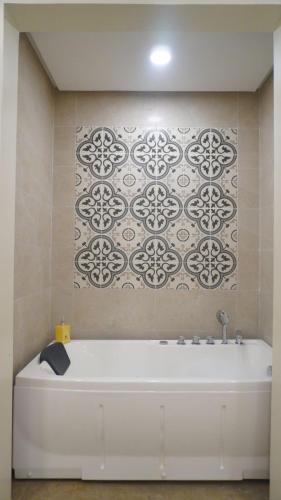 a white bath tub in a bathroom with a tile wall at La Jolla Hotel and Beach Resort in Malawin