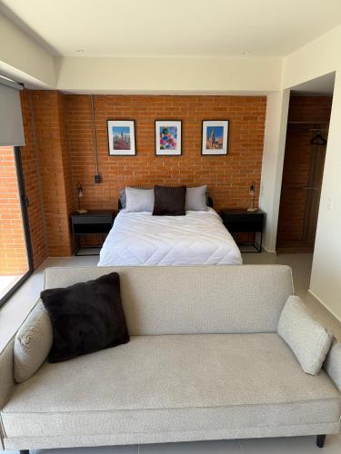 a bedroom with a bed and a couch in a room at Stylish New Loft in Financial Zone and Downtown in Guadalajara