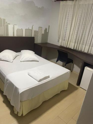 a bed in a room with a desk and a bed sidx sidx sidx at Abbas Hotel in Uberlândia