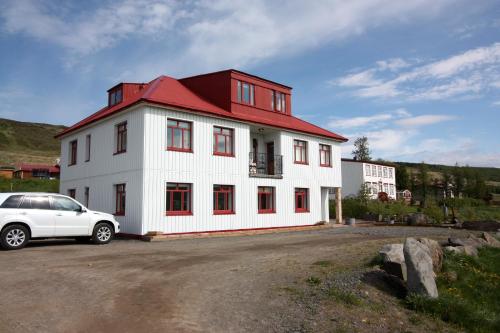 a white house with a red roof and a white car at Guesthouse Storu-Laugar in Laugar