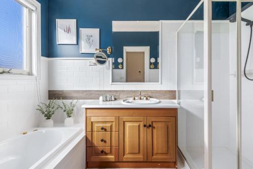 a bathroom with a sink and a tub and a mirror at Spacious Family Home with Balcony in Pascoe Vale in Melbourne