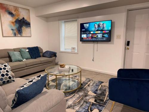 a living room with a couch and a tv on a wall at Cosy Bedroom 6 minutes to EWR Prudential Hotels Pen station in Newark