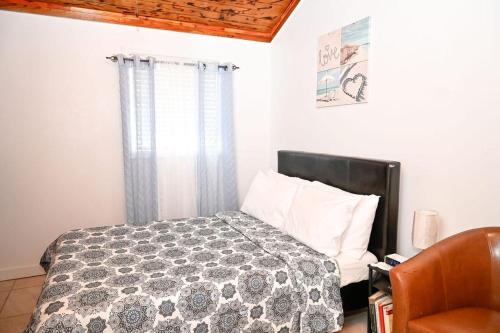 a bedroom with a bed and a chair and a window at Nadiyah's Escape in Rock Sound