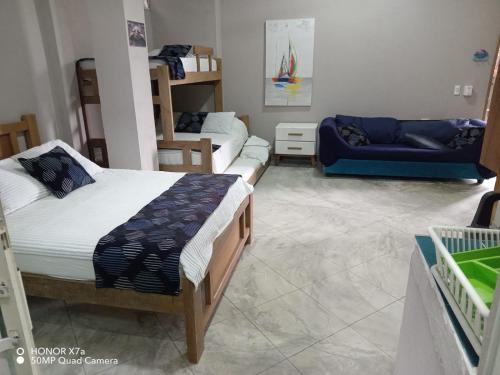 Un dormitorio con dos camas y un sofá azul. en Terraza Del Sol, en Coveñitas