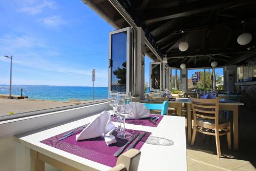 a dining table with a purple napkin and a view of the ocean at Hotel Delfin in Zadar