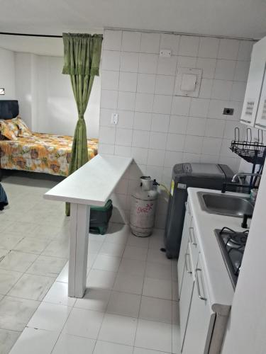 a kitchen with a table and a sink and a bed at Confortable Apartamento Parque Caldas Manizales in Manizales