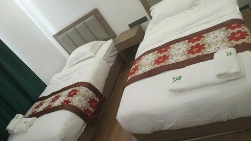 two beds in a small room with white and red sheets at Rainforest Hotel in Paksong