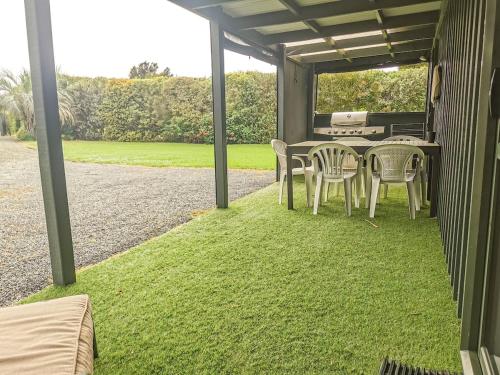 a patio with a table and chairs on grass at Tropical Retreat in Pukenui