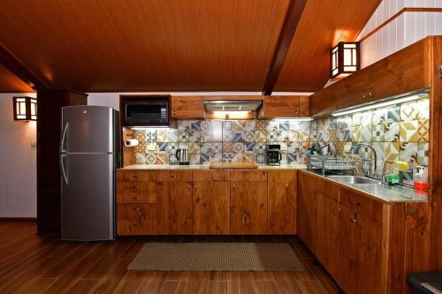 a kitchen with wooden cabinets and a stainless steel refrigerator at Casa Vacacional floreva in Tapantí