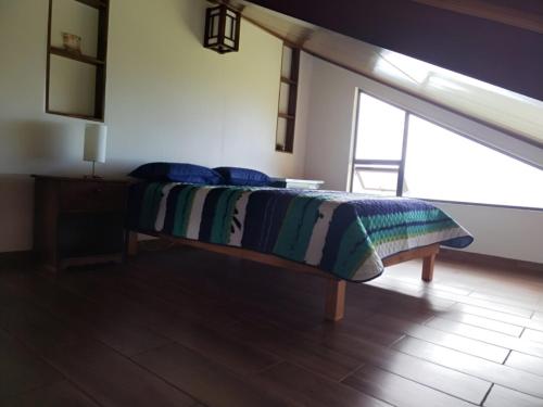 a bed sitting in a room with a window at Casa Vacacional floreva in Tapantí
