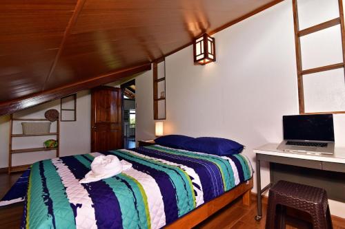 a bedroom with a bed and a desk with a laptop at Casa Vacacional floreva in Tapantí