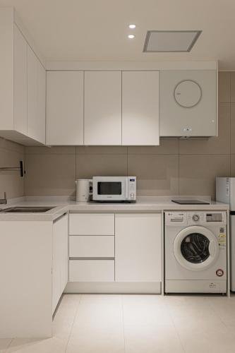 a white kitchen with a microwave and a dishwasher at Hotel Modak Namdaemun in Seoul