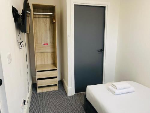 a small room with a bed and a closet at Woodford Hotel in London